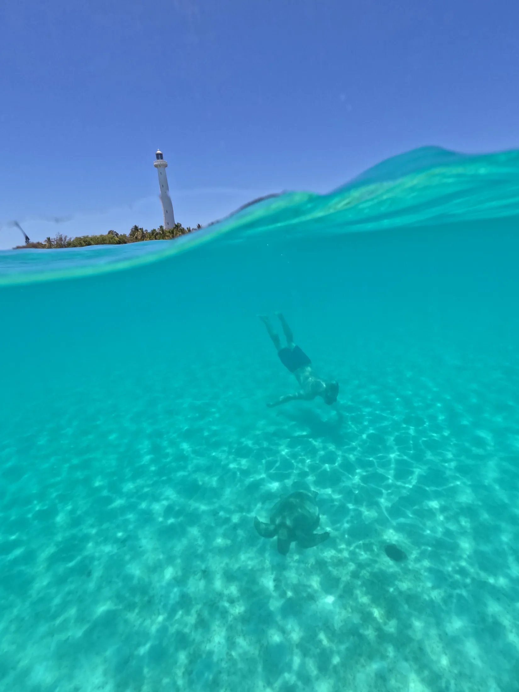 Freediver below the surface with the Amédée lighthouse behind